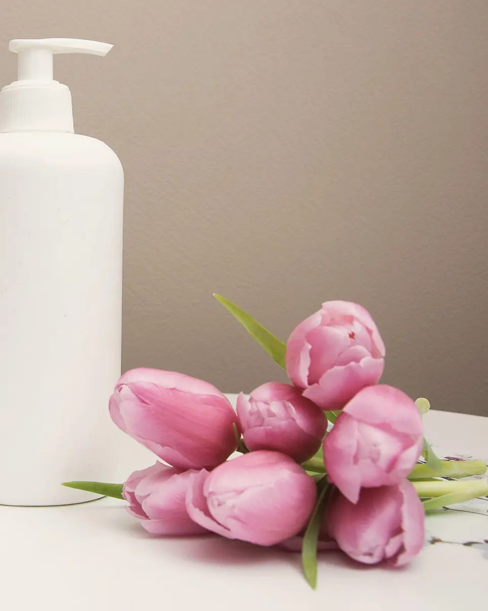 Serviettes roulées, flacon de soin et tulipes roses